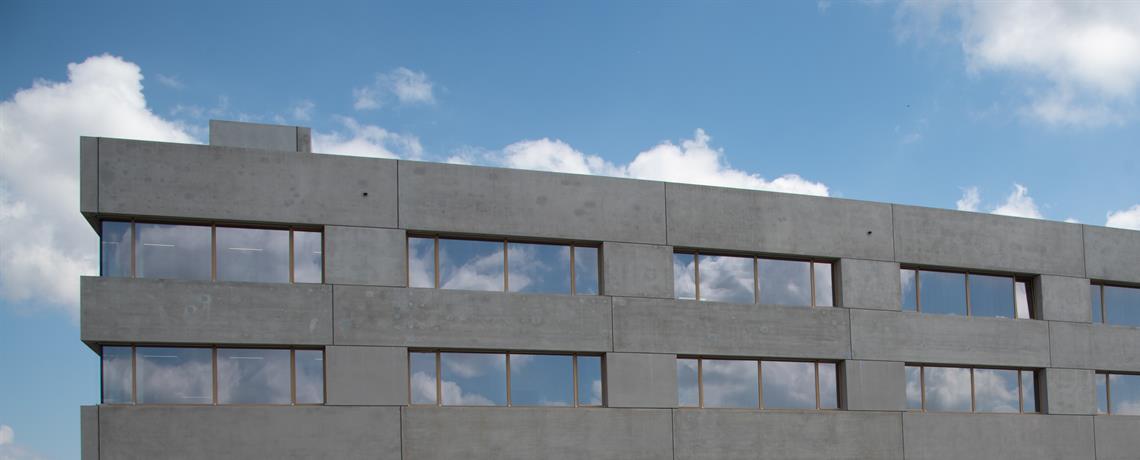 Wolken spiegeln sich in den Fenstern des Neubaus der THU am Campus Albert-Einstein-Allee.